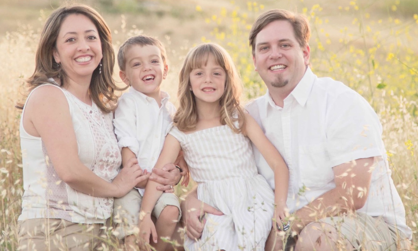 Dr. Faranak Herrera posing in a medow with her husband and two children